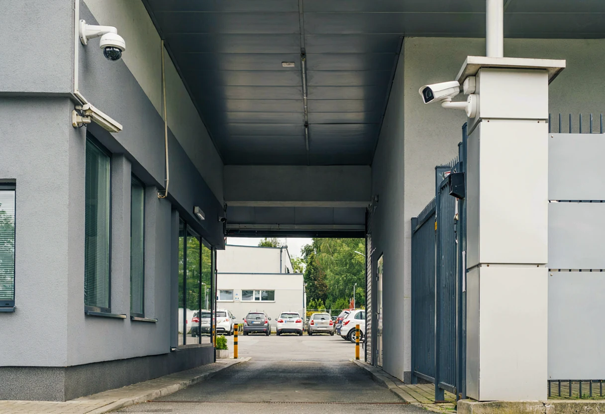 Dwa punkty kamer przy wejściu i parkingu niewielkiego obiektu – ilustracja AI.